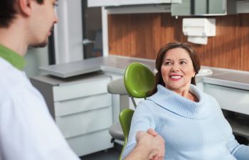 Mature Female Patient in Dental Chair Shaking Hands with Dentist