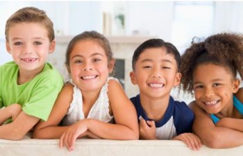 group of four happy children showing teeth in their smiles
