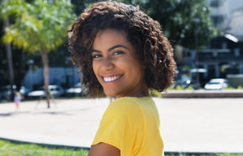 Young smiling Afro-American woman showing beautiful white teeth after dental cosmetic treatments