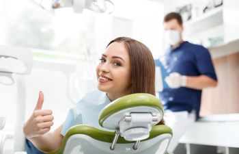 smiling teenage girl in a dental chair showing her thumb up